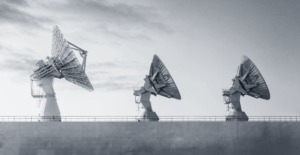 Three large, white satellite dishes against a cloudy sky, representing advanced technology for compliance monitoring.